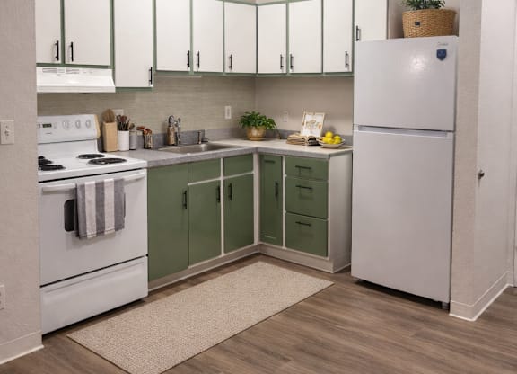 A kitchen with white cabinets and a white refrigerator.