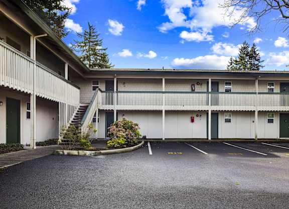 A parking lot in front of a white building with green doors.