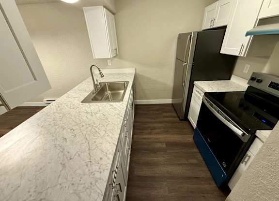 A kitchen with a sink, refrigerator, and oven.