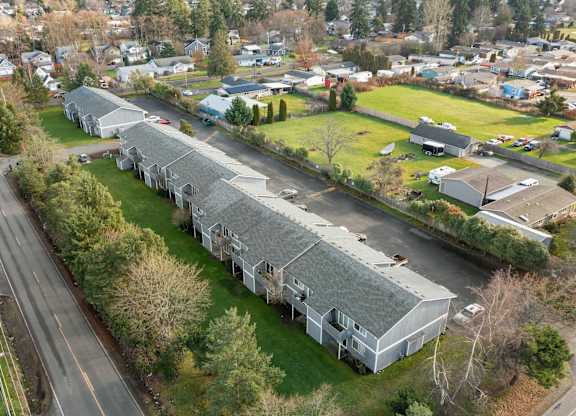 A long white building with a grey roof sits in the middle of a grassy area.
