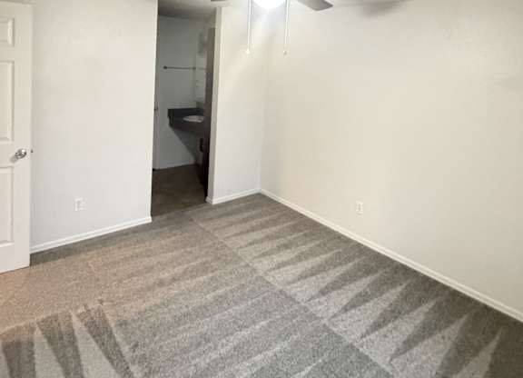 A room with a ceiling fan and carpeted floor.