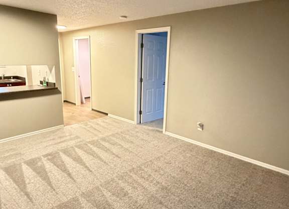 A room with a carpeted floor and a door on the right.