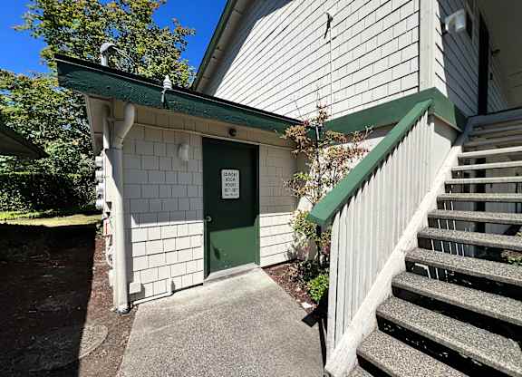 A green door is on a white building with a green awning.