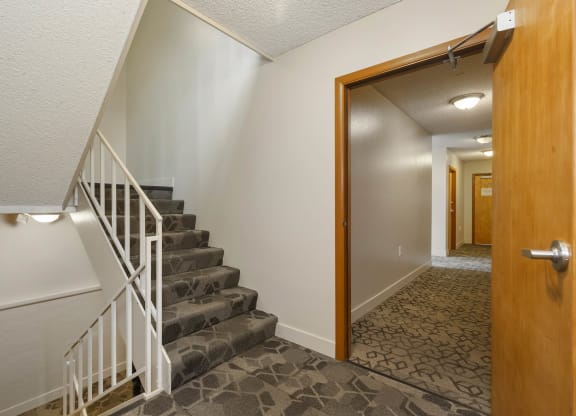 the landing of a staircase in a home with a door open to a hall way