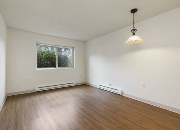 an empty living room with wood floors and a window