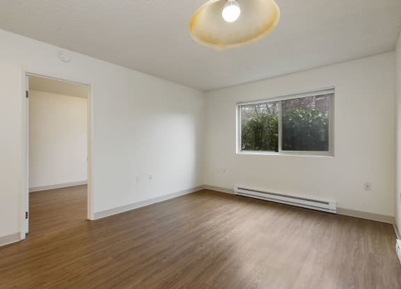 an empty living room with wood floors and a window