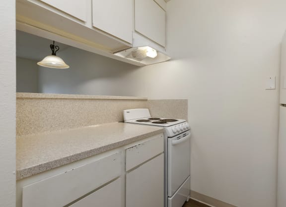 a kitchen with white appliances and a counter top with a stove and a refrigerator
