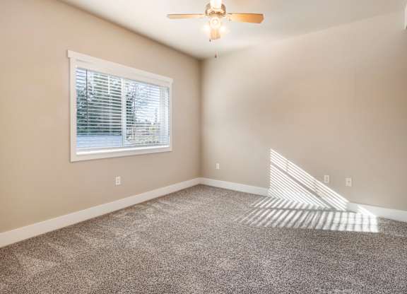 A room with a ceiling fan and a window with blinds.