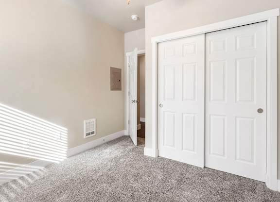 Primary bedroom with closet doors and a carpeted floor.