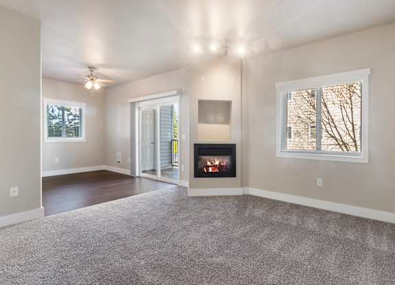 A spacious living room with a fireplace and a ceiling fan.