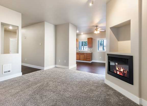 A living room with a fireplace and a grey carpet.
