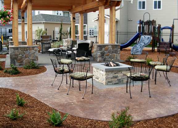 A patio with a firepit and chairs.