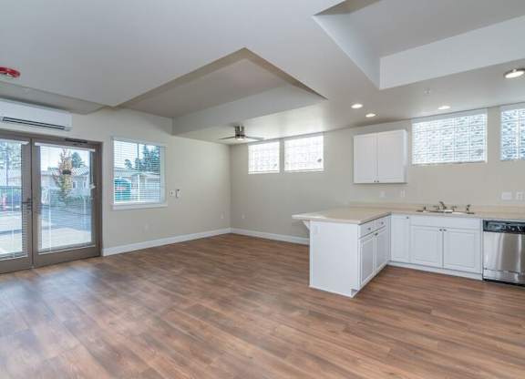 A large, empty kitchen with wooden floors and white cabinetry.