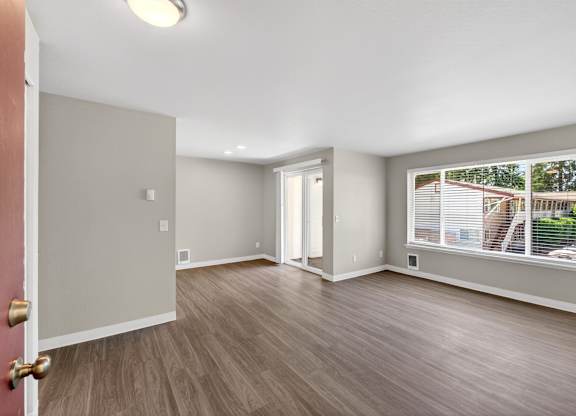 A room with a wooden floor and a red door.