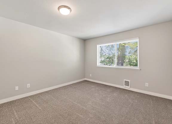A room with a window and a carpeted floor.