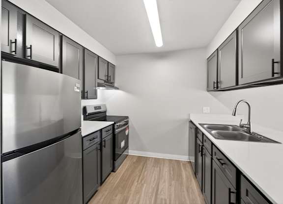 A modern kitchen with stainless steel appliances and black cabinets.