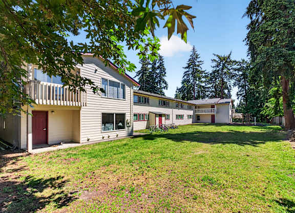 A large, well-maintained lawn in front of a two-story house with a red door.