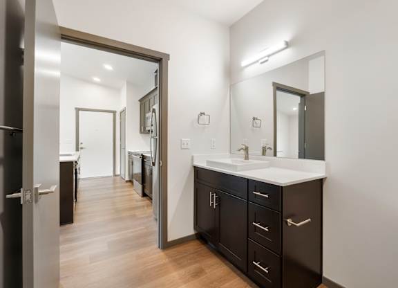A bathroom with a sink, mirror, and cabinets.