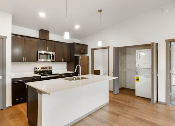 A modern kitchen with a white island and dark brown cabinets.