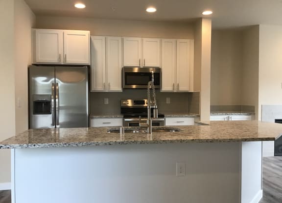 a kitchen with white cabinets and a granite counter top