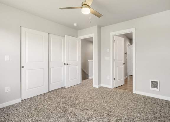A room with a ceiling fan and carpeted floor.