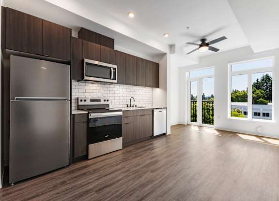 A modern kitchen with a refrigerator, microwave, oven, and sink at The Hub Apartments, Lacey, WA