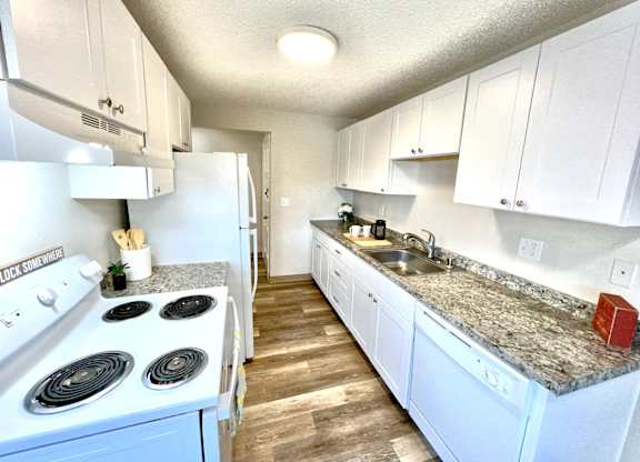 A kitchen with white cabinets and a white stove top oven.