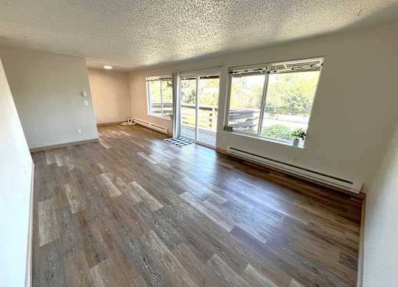 A room with wooden flooring and sliding glass doors.