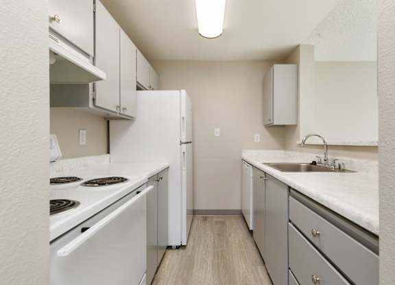 A kitchen with white appliances and grey cabinets.