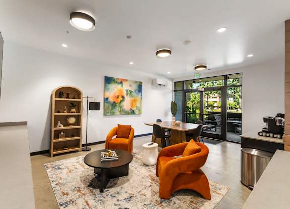 A living room with a rug, a chair, a table, and a painting on the wall at The Hub Apartments, Lacey, 98503