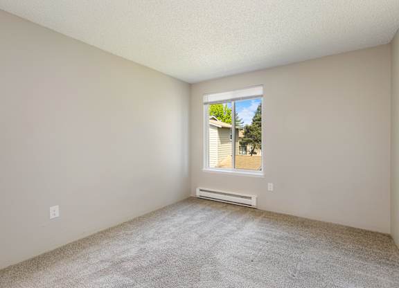 A bedroom with a window and a carpeted floor.
