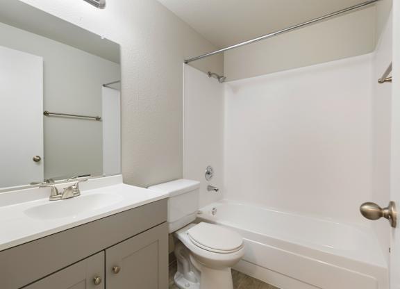 A bathroom with a toilet, sink, and bathtub and shower combo.