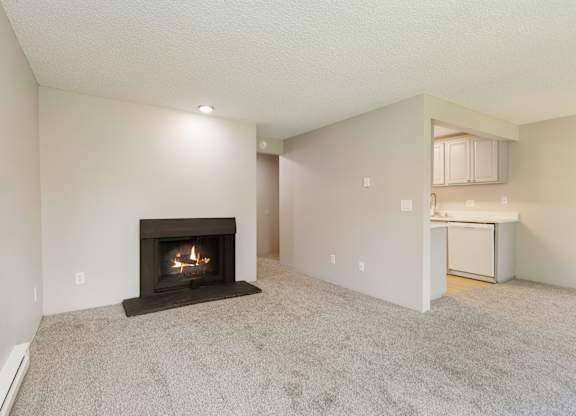 A Livingroom with a fireplace and a carpeted floor in a 1 bedroom apartment at Hillcrest Estates in Everett, WA..