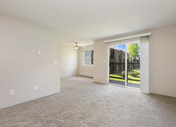 A Living Room with a carpet floor and sliding glass doors leading to a balcony.