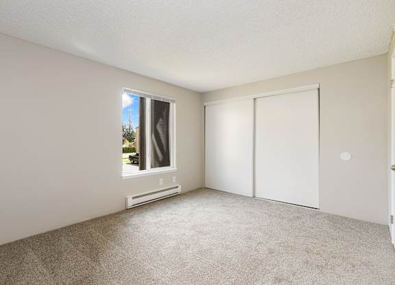 A bedroom with a window and a closet.