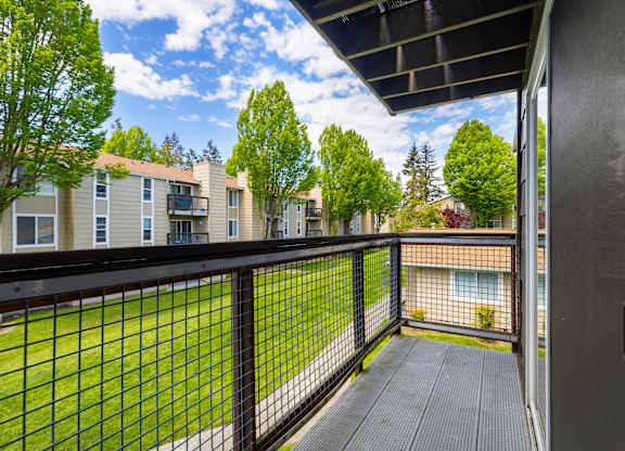 A balcony with a black railing and a view of apartment buildings.