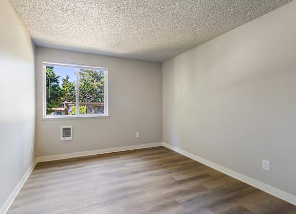 A room with a window showing a view of trees and a house.