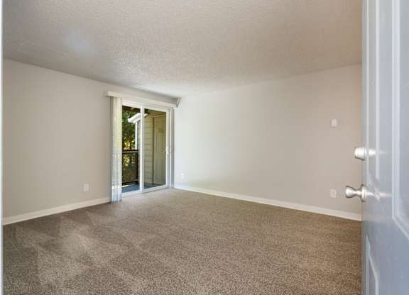 A room with a carpeted floor and a door leading to a hallway.