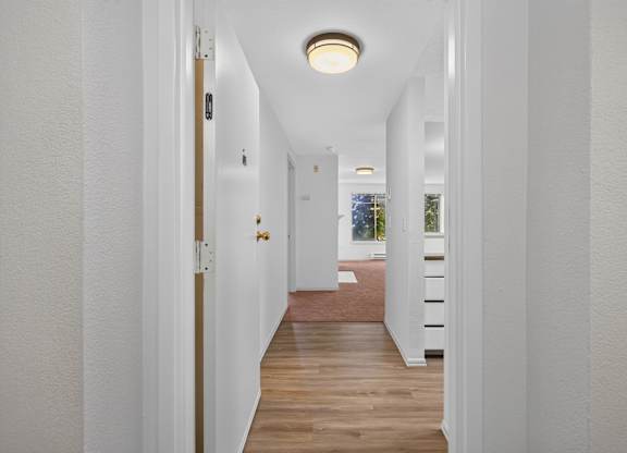 A long hallway with white walls and wood floors.