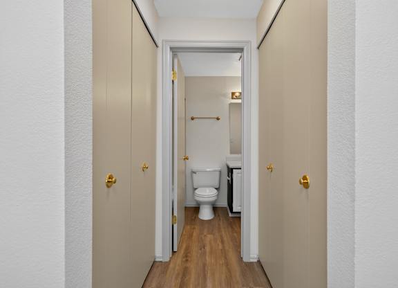 A white door with a gold handle is open to a small bathroom.