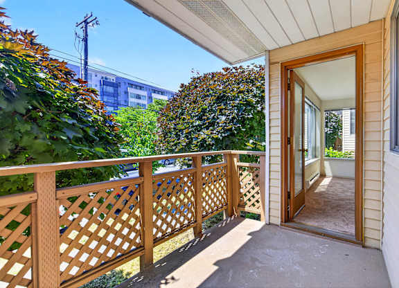 A wooden balcony with a lattice design and a doorway leading to the interior of a house.