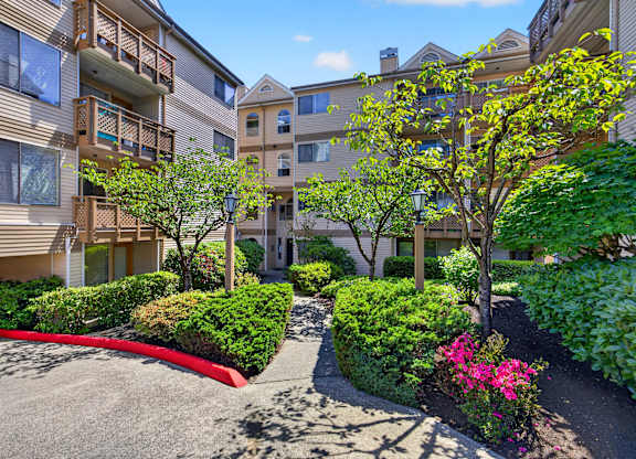 A sunny day at a residential complex with apartment buildings and landscaped gardens.