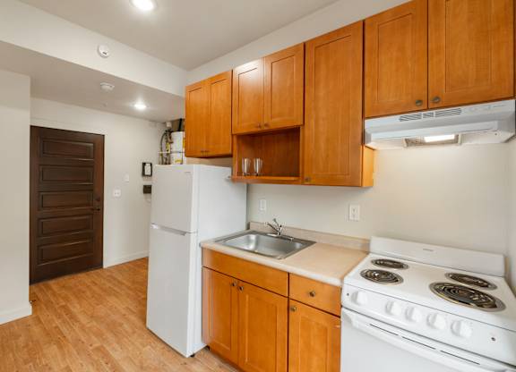 A kitchen with wooden cabinets and a white stove top oven.