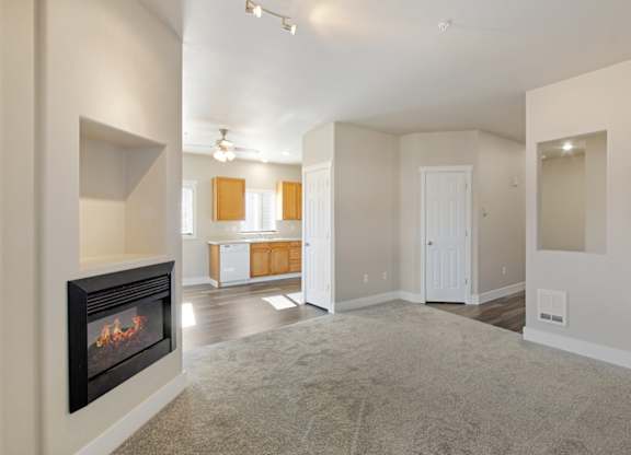 Living room with carpet and fireplace and view to kitchen at Hearthstone Apartments