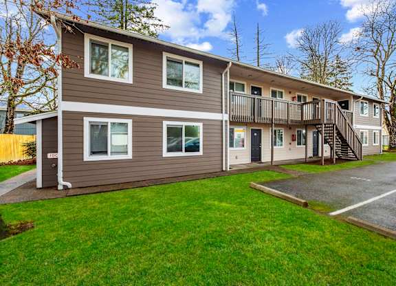 A two-story apartment building with a parking lot in front.