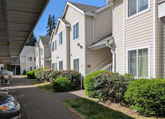 A residential street with houses on both sides and a car parked on the left.