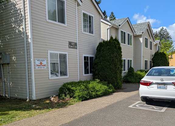 A white car is parked in a parking spot in front of a building.