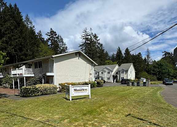 A grassy area with a sign that says "Maurice" in front of a building.