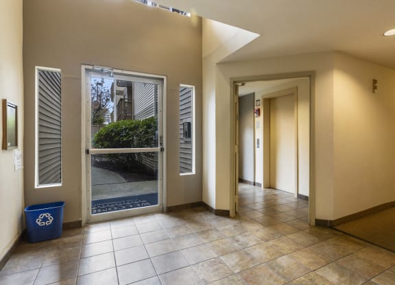the lobby of a building with an open door and tiled floors