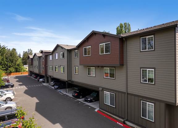 A row of townhouses with a parking lot in front.